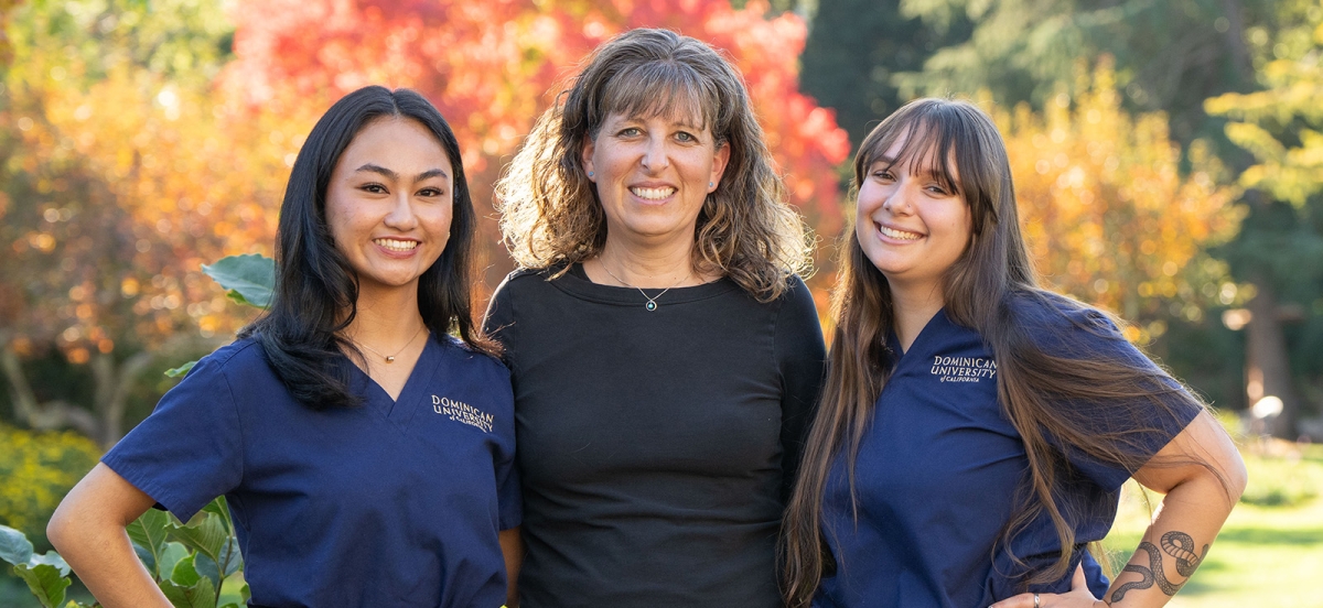 2 nursing students and a professor smiling