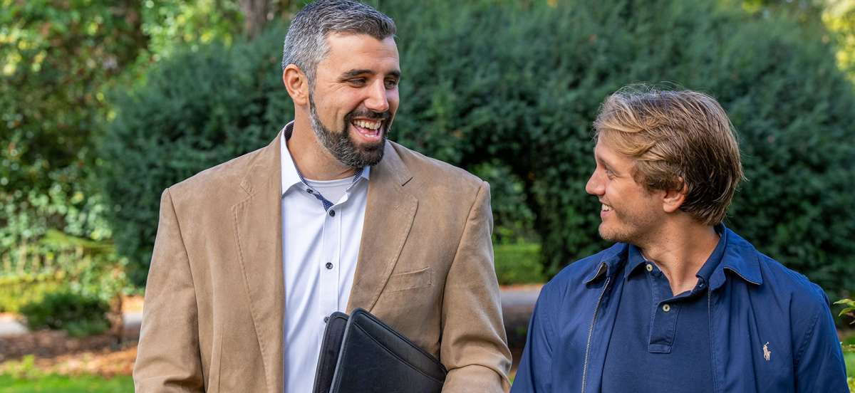 history professor and student walking outside laughing and smiling