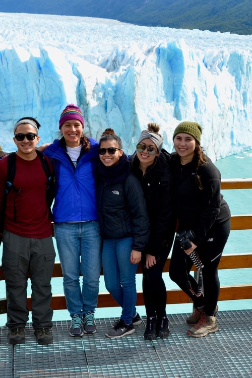 Group of people standing against railing with view of glacier in the background
