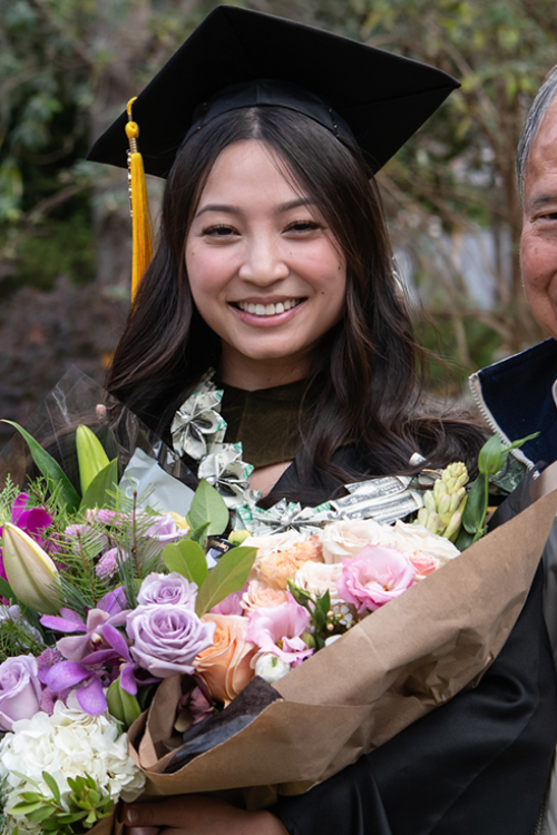 graduate holding a bouquet of flowers with grandparent