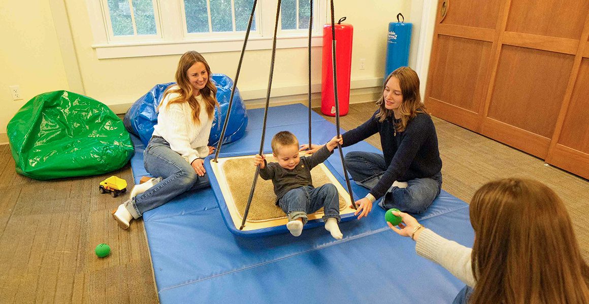 3 occupational therapy students engaging with a child in the OT lab