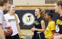Five Dominican University of California women's basketball team members talking in the gym during practice.