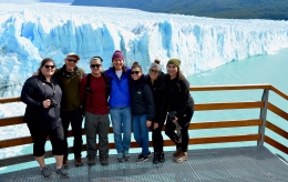 Group of people standing against railing with view of glacier in the background