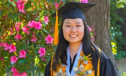 Photo of Marissa Vang in cap and gown with flowery backdrop on Dominican campus