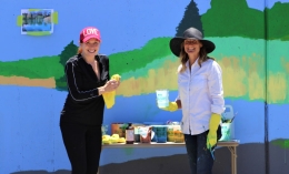 photo of Lynn Sondag (right) and neighbor Julie Coyle posing in front of colorful mural painted on retaining wall in California Park neighborhood