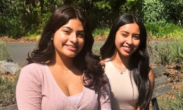 Photo of Brittany Santos '22  (right) and Sofia Esteva '23 sitting on bench side by side and facing camera on edge of Meadowlands Hall Lawn