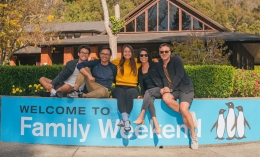 Dominican family sitting and posing on wall with "Welcome To Family Weekend" banner