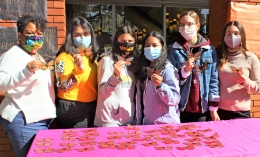 DEI Director Stacy Davidson (left) and five student members of IGNITE Club pose with butterfly pins in front of table at Caleruega Dining Hall