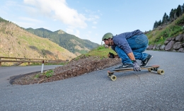 Former pro skateboarder James Kelly, a now a nursing student, squats on his longboard making a downhill turn on a winding road in Italy