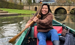 Photo of Dominican Scholar Christina Pathoumthong smiling while sitting in a boat rowing in canal through the University of Oxford campus 