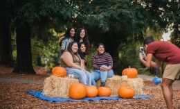 students posing for photo with haystacks and pumpkins