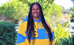 Photo of Dominican alumna La Donna Clark smiling and posing wearing hoodie with Golden State Warriors (blue and gold) 