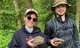 Students Alison White (left) with sunglasses and Nathan Green (with camouflaged hat) standing and posing with each holding a turtle in their hands