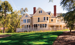 Edgehill Mansion on the Dominican Campus, a Victorian-style mansion with beige exterior, red brick chimneys, and a wrap-around porch on a sunny lawn.