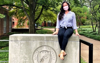Dominican alumna Samantha Hunt wears a mask while sitting on concrete wall on Vanderbilt campus