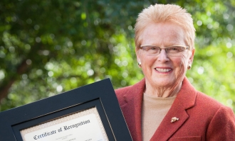 Fran Lepage posing with a framed award certificate