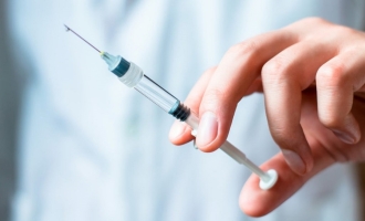 Stock photo of hand holding needle syringe for vaccine side effects study story