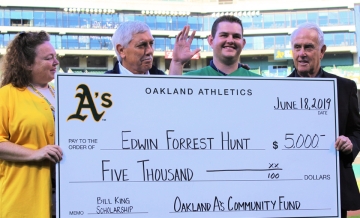 Photo of Forrest Hunt receiving  cardboard check for $5,000 on field before Oakland A's game flanked to the left by the late Ray Fosse and to the right by Ken Korach, both A's announcers
