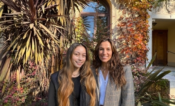 Two women smile at the camera outside Guzman Hall on the Dominican campus