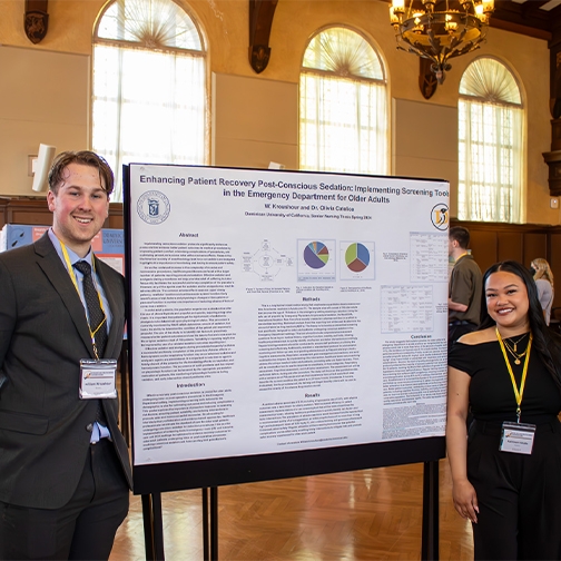 Two students standing next to their research poster.