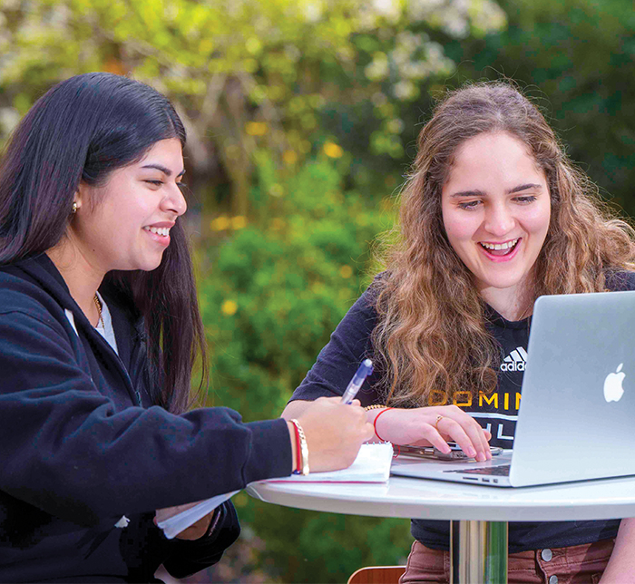 two students working on laptop and smiling
