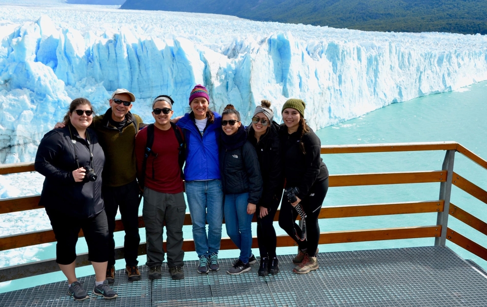 Group of people standing against railing with view of glacier in the background