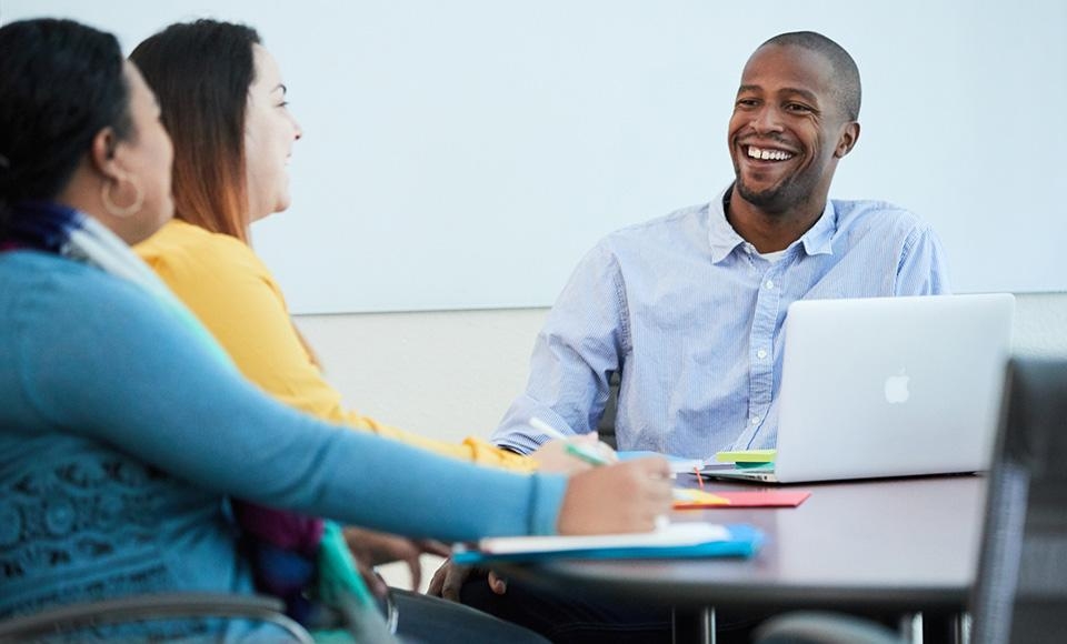 students talking with open laptop