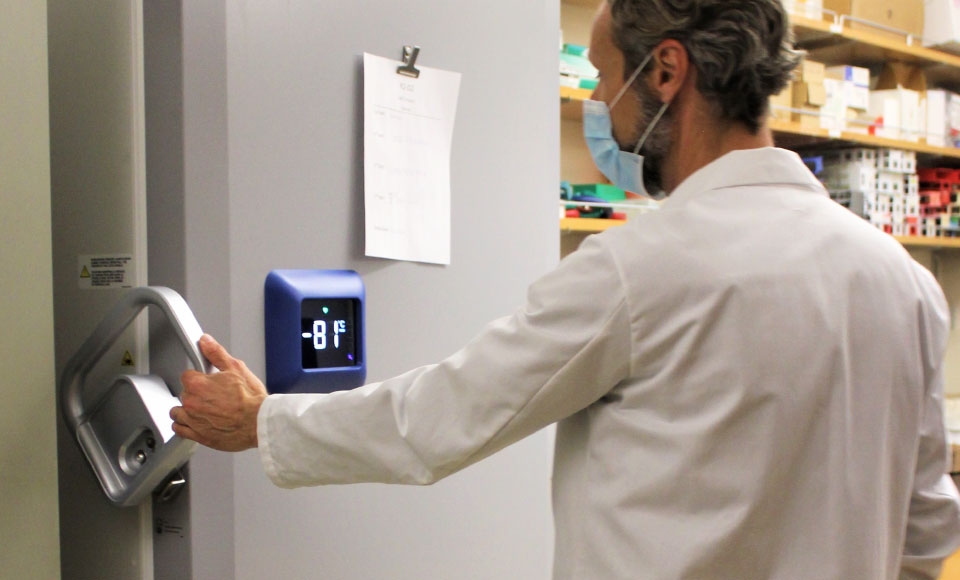Photo of Professor Chris Endicott opening door of freezer in Science Building that will store COVID-19 vaccine