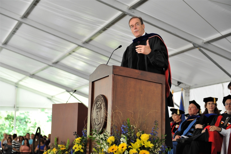 Photo of retired head of Student Life John Kennedy on stage at podium for 2013 Commencement