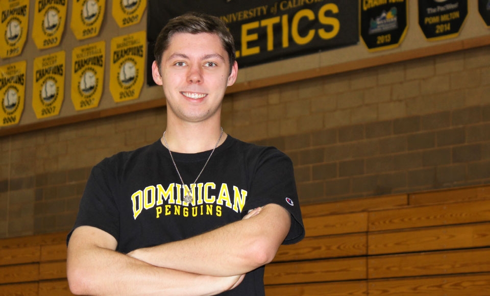 Photo of Matthew Kodweis '21 standing in Conlan Center gym with black and yellow athletics banners in background