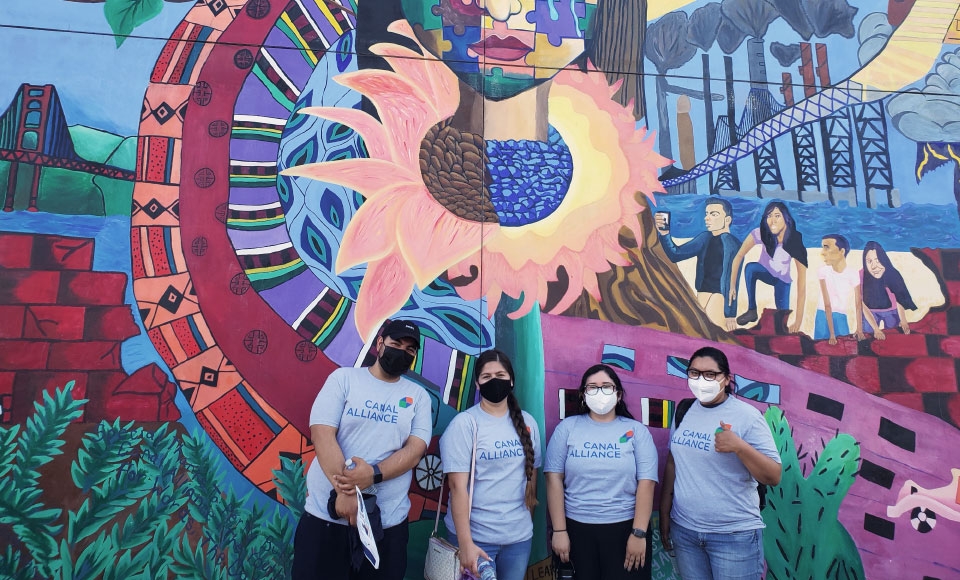 Photo of Dominican students standing in front of colorful mural at Canal Alliance for HP image/story about community partnership developing rental assurance program