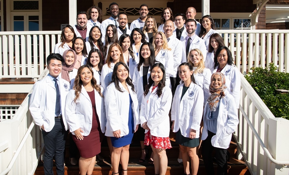 Photo of Dominican's MSPAS Class of 2022 smiling and posing with their white coats for group shot on steps of Meadowlands Hall