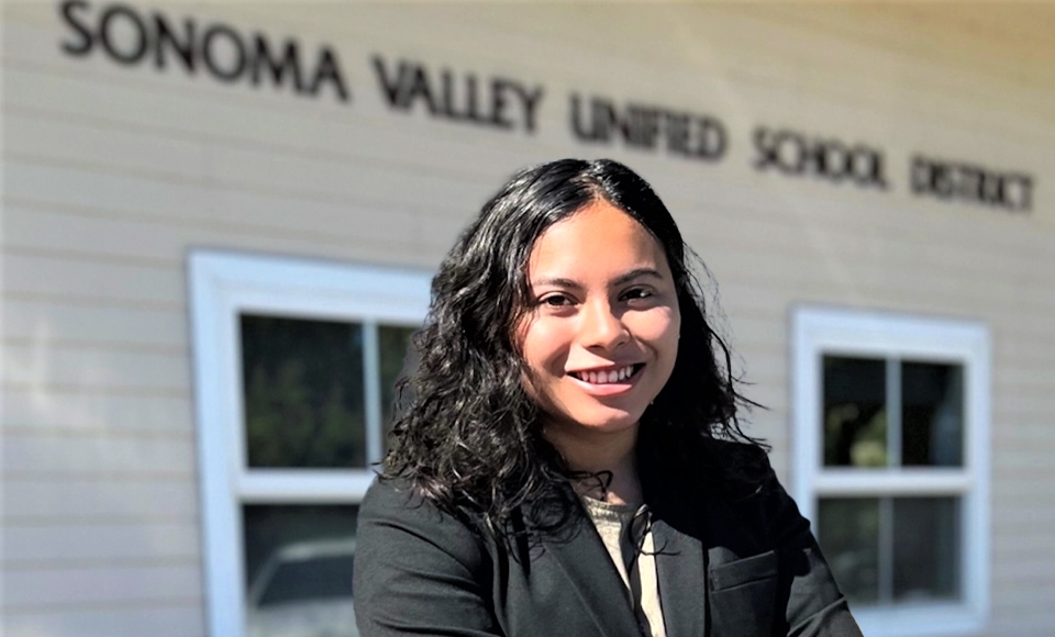 Photo of Jacquelyn Torres '22 in black top standing outside tan Sonoma Valley Unified School District building 