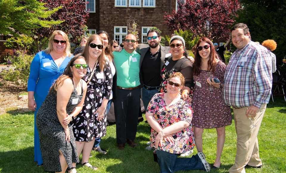 Photo of group of 10 alumni posing and smiling on Meadowlands Hall lawn at 2022 Reunion Weekend
