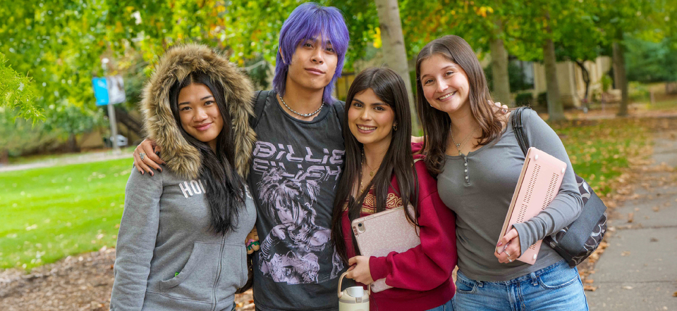 Group of 4 students outside embracing eachother.