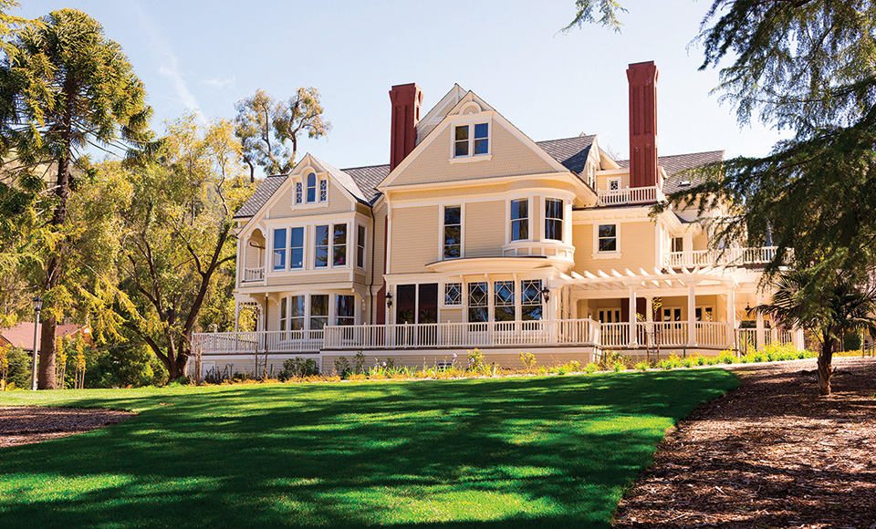 Edgehill Mansion on the Dominican Campus, a Victorian-style mansion with beige exterior, red brick chimneys, and a wrap-around porch on a sunny lawn.