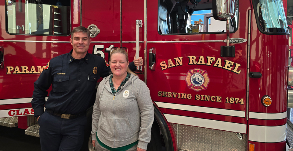 San Rafael firefighter and Dominican program director in front of a fire engine.